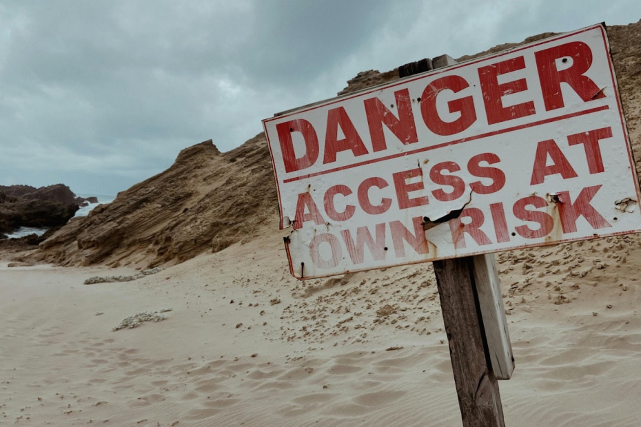 A sign in the sand that reads Danger: Access at own risk written in large red letters. Illustrating the fear I felt about leaving the LDS church.