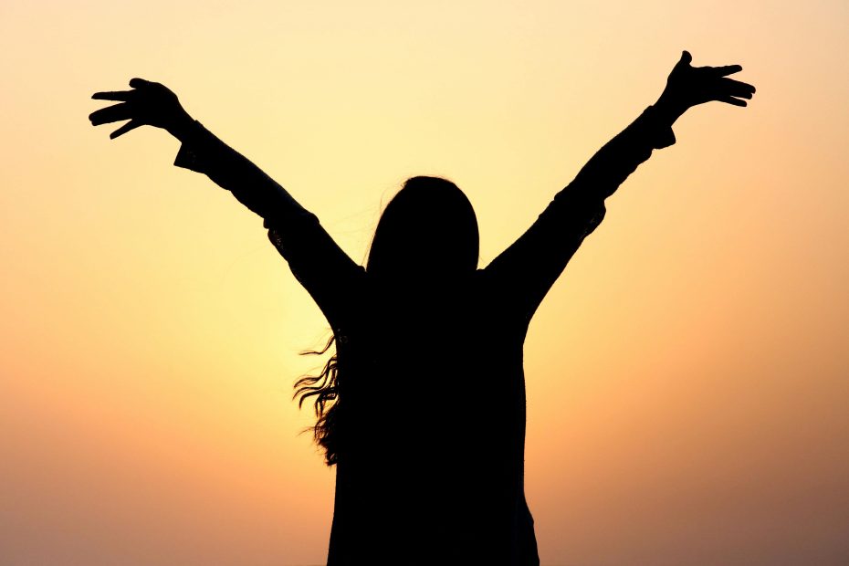 A silhouette of a woman with her arms up and spread in joy facing the sun, illustrating the freedom and joy I found when I became exmormon.