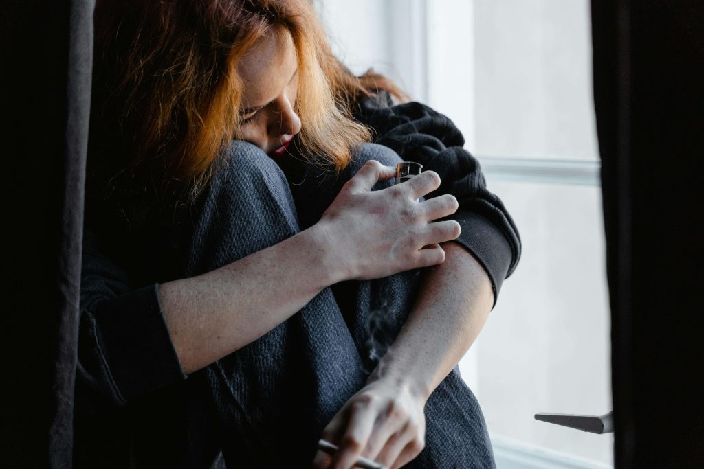 A woman hugging herself small while smoking a cigarette, illustrating the fear of being left to myself if I left the LDS church.